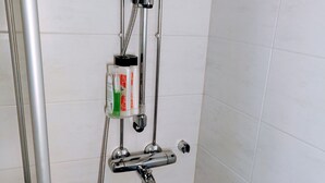 Una ducha con cabezal de ducha manual, un accesorio de ducha manual y un cabezal de ducha de pared.