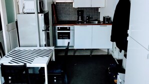 Una cocina compacta con gabinetes blancos, microondas, cafetera y tostadora.