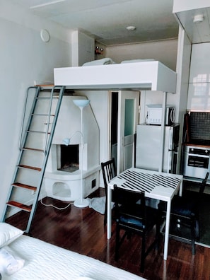 Een compact studio-appartement met een slaapverdieping, een kitchenette en een klein eethoekje.
