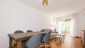 Ein modernes Wohnzimmer mit einem Holzesstisch, blauen Stühlen, einem grauen Sofa und einem kleinen runden Tisch.