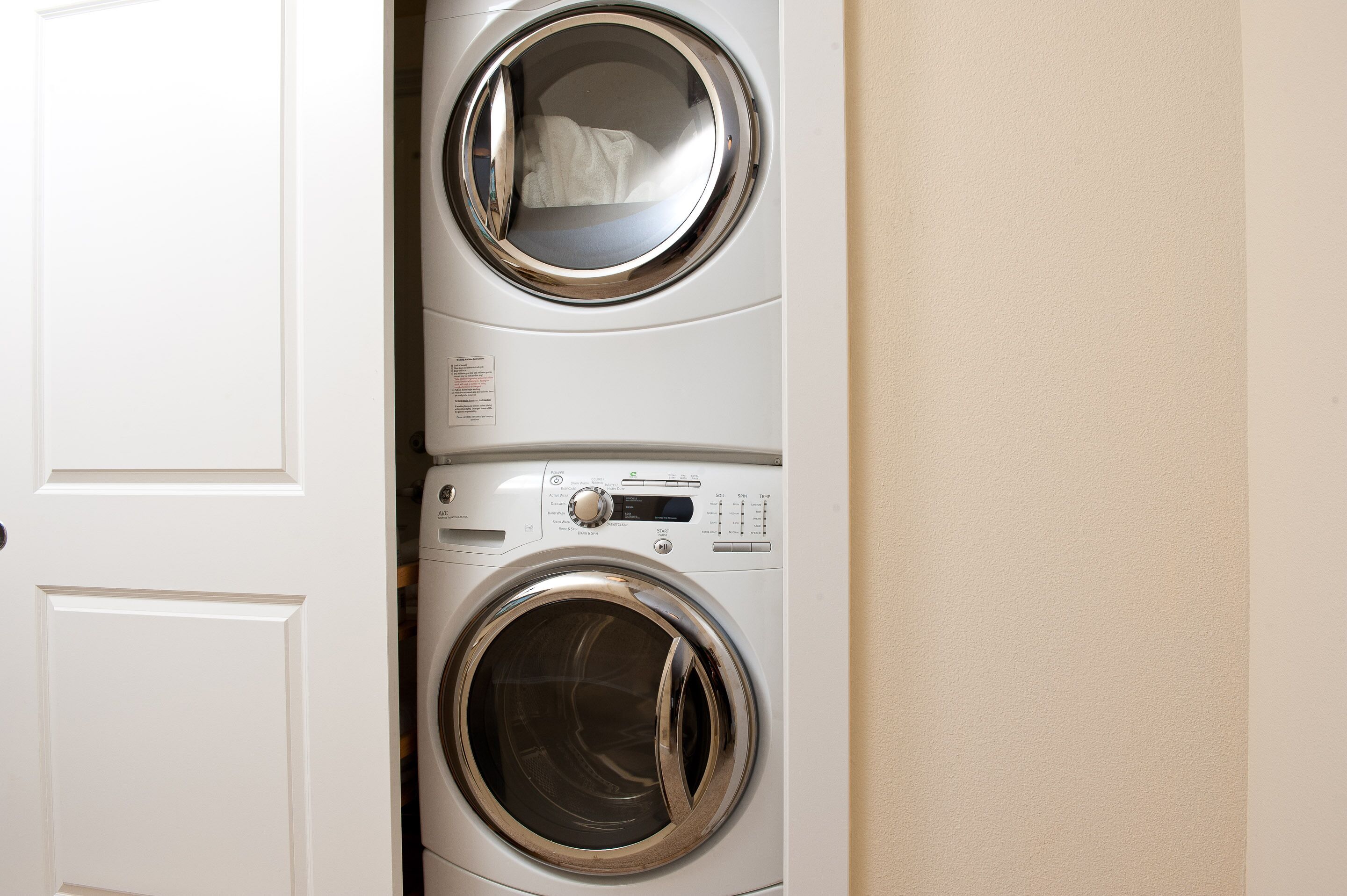 Vue de face d’un lave-linge à double porte, avec un panneau de commande et un miroir sur la porte.