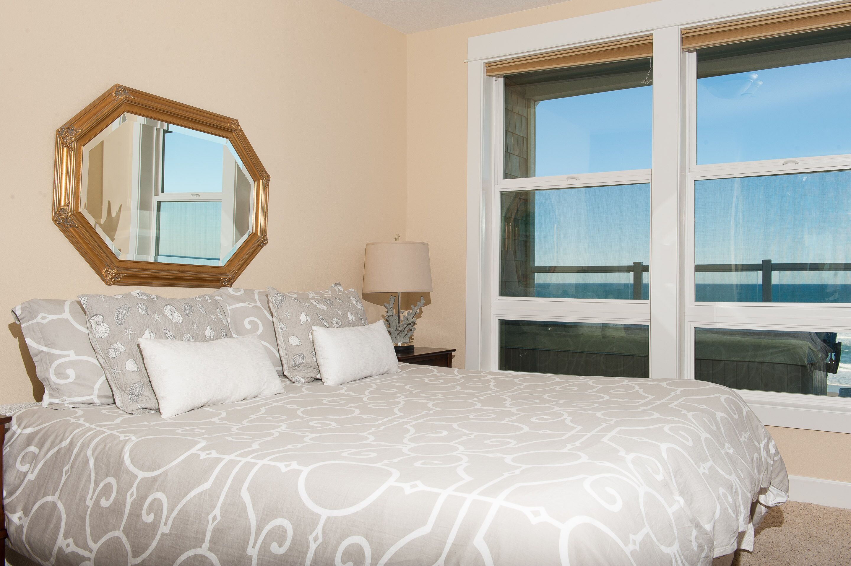 A bedroom with a large bed, a nightstand, a lamp, and a window with a view.