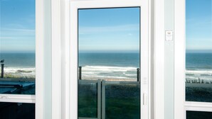 Une vue sur l’océan et la plage, prise à travers une porte, avec un ciel dégagé et un panneau sur le mur.
