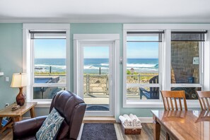 Una habitación con vista al océano, un sillón de cuero, una mesa y una lámpara.