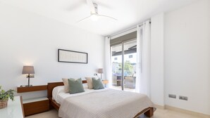 A bedroom with a bed, bedside lamps, a nightstand, a window with curtains, and a ceiling fan. - Penthouse with pool view - UHC SALOU VILLA FAMILY COMPLEX 029 (Salou)