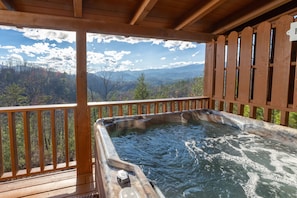 A hot tub on a wooden deck with a scenic mountain view.