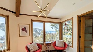 A corner room with two red chairs, a small table, and large windows offering a mountain view. - Pet friendly (with fees) Great views (Keystone)