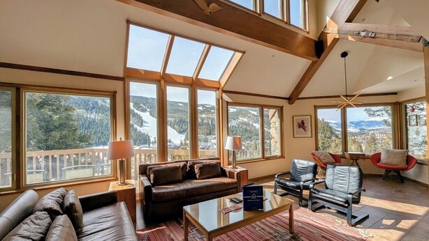 A spacious living room with a large window overlooking a mountainous landscape, a leather sofa, a glass coffee table, and modern chairs. - Pet friendly (with fees) Great views (Keystone)