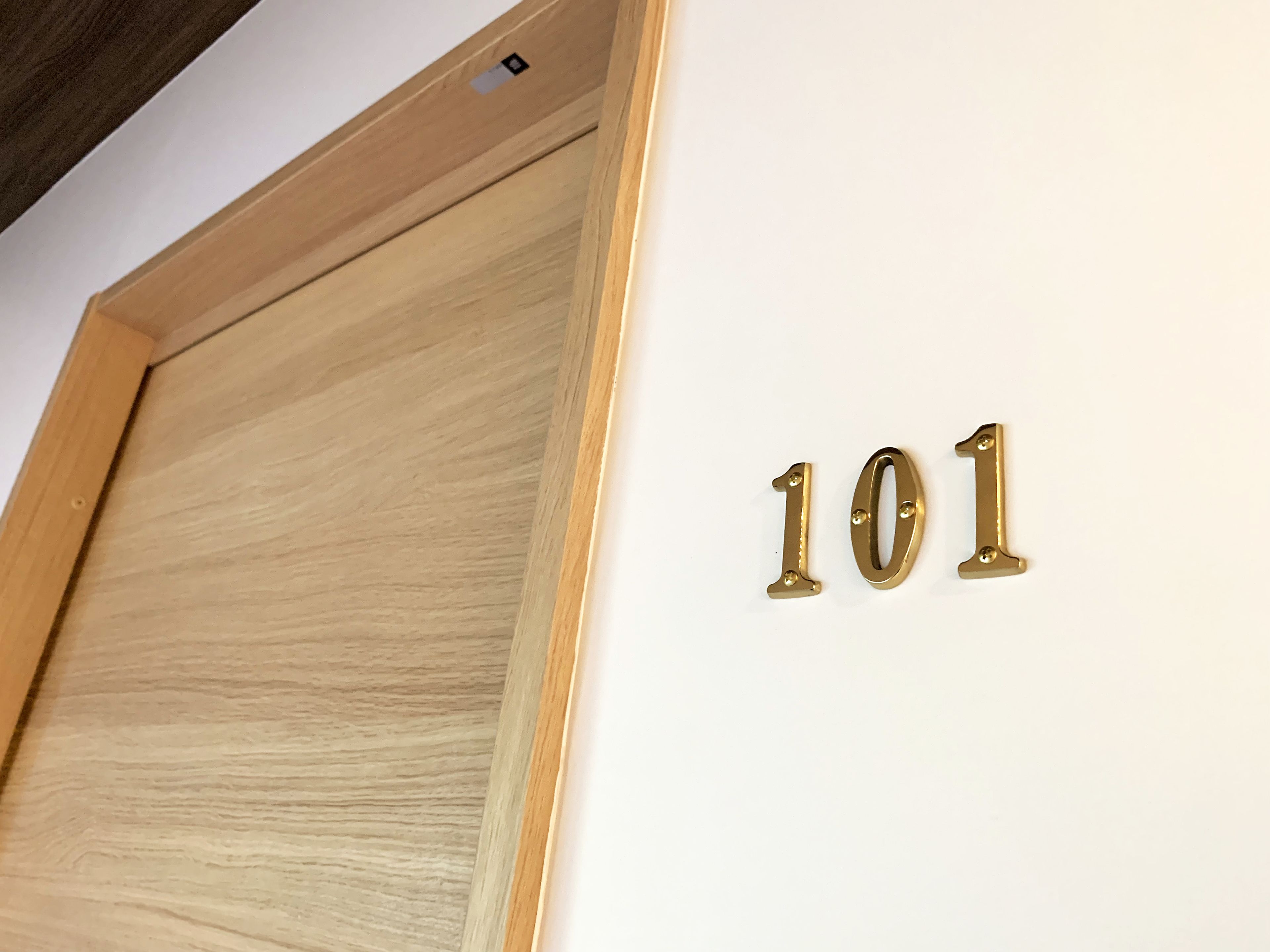 A wooden door with a brass number plaque indicating room number 101.