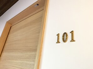 A wooden door with a brass number plaque indicating room number 101.