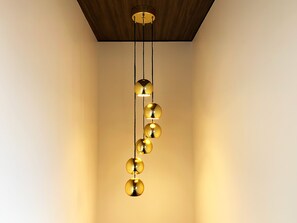 A modern chandelier with spherical light fixtures hanging from a ceiling with a wooden panel design.