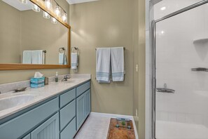 Un bagno con doppio lavabo, uno specchio, asciugapiatti e zona doccia.