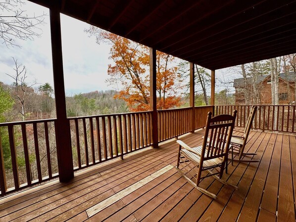 A wooden deck with a railing, a chair, and a table. - Mtn Views! Pool Table, Hot Tub, Air Hockey & Free Access to Pool, Golf, Fishing (Sevierville)
