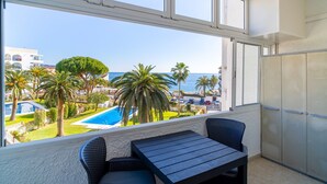A balcony with a view of a swimming pool, palm trees, and the sea. - Carabeo 27 Studio by Casasol (Nerja)