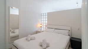 A hotel room with a large bed, a nightstand with a lamp, a ceiling fan, and a window with blinds. - Carabeo 27 Studio by Casasol (Nerja)