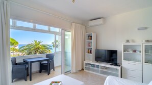 A modern living room with a balcony, a flat-screen TV, a bookshelf, and a white sofa. - Carabeo 27 Studio by Casasol (Nerja)
