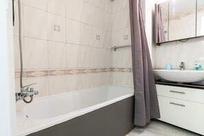 Bathroom features a large bathtub, sink, and shower area with a shower curtain.