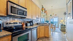 A modern kitchen with stainless steel appliances, wooden cabinets, and a granite countertop. - FFR310 - Ocean Sky by First Flight Rentals (Kill Devil Hills, NC 27948)