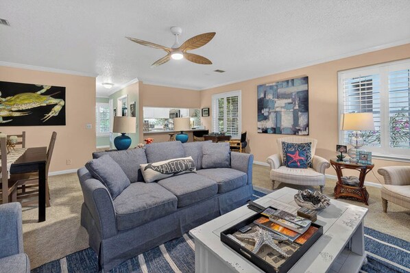 A living room with a grey sofa, a coffee table, and a ceiling fan.