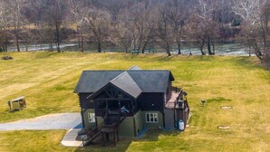 A large, two-story log cabin with a porch and a staircase leading to the upper level.