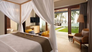 A bedroom with a large bed, a TV, a desk, and a view of a pool and palm trees.
