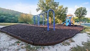 A playground with a slide and climbing structures, surrounded by trees and a clear sky. - 24-6 Serenity Escape Penthouse w/Indoor/Outdoor Pool / Splash Pad Near SDC (Branson)