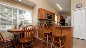 A kitchen with wooden cabinets, a microwave, and a dining area with wooden chairs. - 24-6 Serenity Escape Penthouse w/Indoor/Outdoor Pool / Splash Pad Near SDC (Branson)