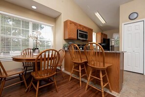 Una cocina con armarios de madera, un microondas y un comedor con sillas de madera.