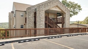 A building with a stone facade, a wooden balcony, and a parking area. - 24-6 Serenity Escape Penthouse w/Indoor/Outdoor Pool / Splash Pad Near SDC (Branson)