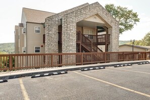 Un immeuble avec une façade en pierre, un balcon en bois et un parking.