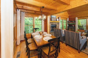 A wooden cabin dining area with a table set for four, a fireplace, and a view of the outdoors.