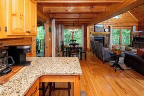 A wooden cabin interior with a kitchen, dining area, and living room.