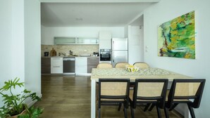 A modern kitchen with white cabinets, a dining table with four chairs, and a painting on the wall. - Spacious 3BR Apartment Near Tel Aviv Beach (Tel Aviv)