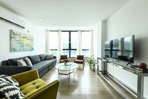 A modern living room with a sofa, armchairs, a coffee table, and a TV.