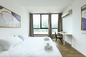 Une chambre d’hôtel avec un lit, un bureau et une fenêtre.