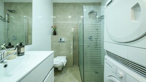 A modern bathroom with a toilet, sink, and glass shower enclosure. - Spacious 3BR Apartment Near Tel Aviv Beach (Tel Aviv)