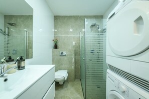 A modern bathroom with a toilet, sink, and glass shower enclosure.