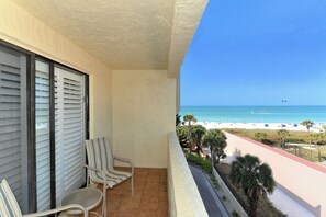 A balcony with two chairs, a view of the beach, and a clear sky. - Spectacular Beach View Steps from Siesta Key Beach! (Sarasota)