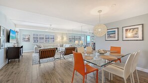 A modern living room with a glass dining table, orange chairs, and a large woven pendant light. - Spectacular Beach View Steps from Siesta Key Beach! (Sarasota)