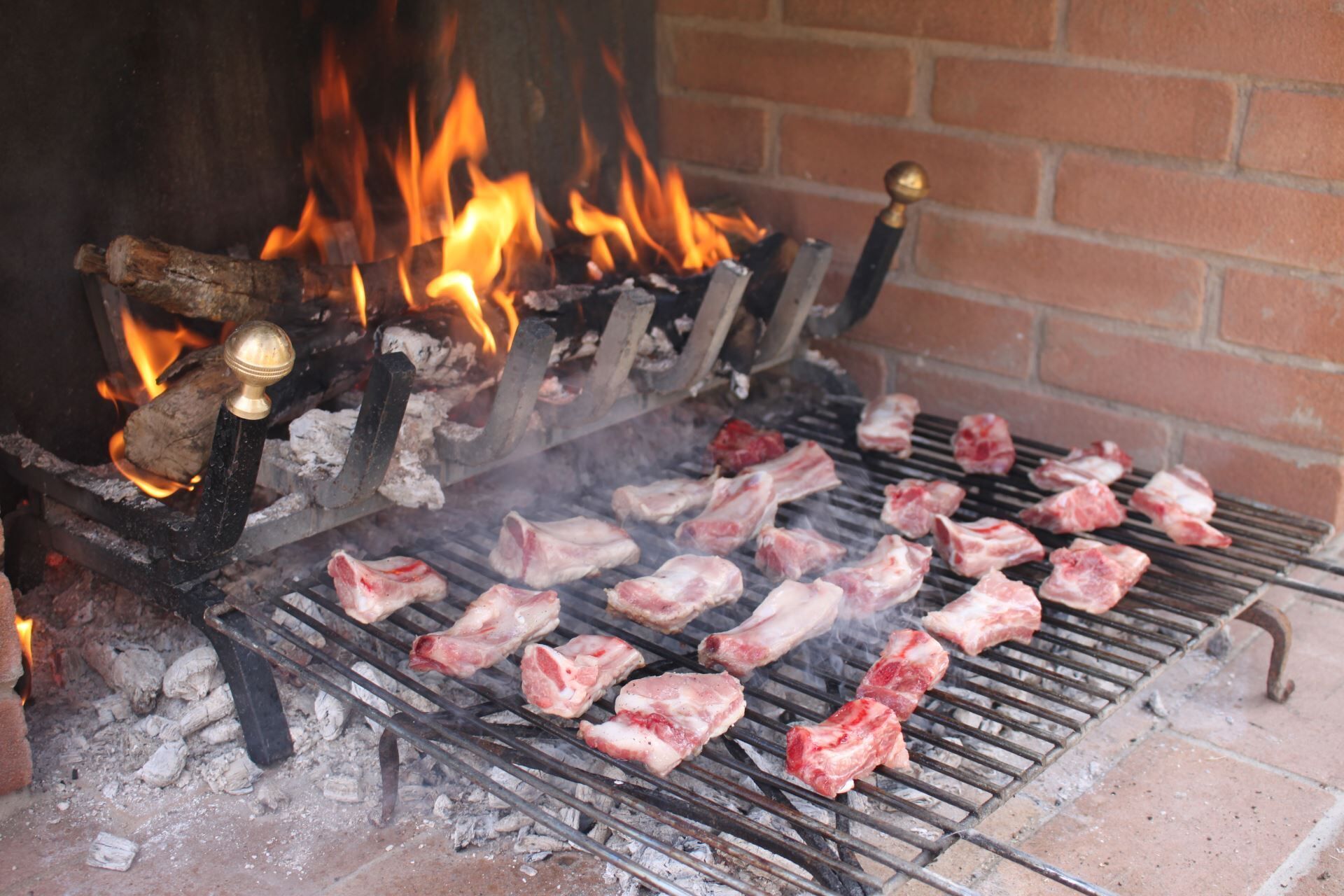 Una graella amb carn crua que es cou sobre foc obert.