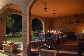 An outdoor dining area with brick arches, tables set for dining, and potted plants.