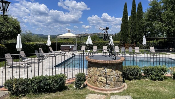 Un espace piscine avec des chaises longues, un barbecue et une vue sur le paysage.