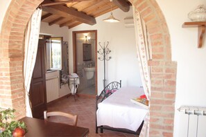 A rustic bedroom with a bed, a wooden table, and a chair.