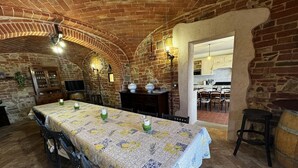 Un coin repas rustique avec une longue table, des chaises et un plafond en briques.