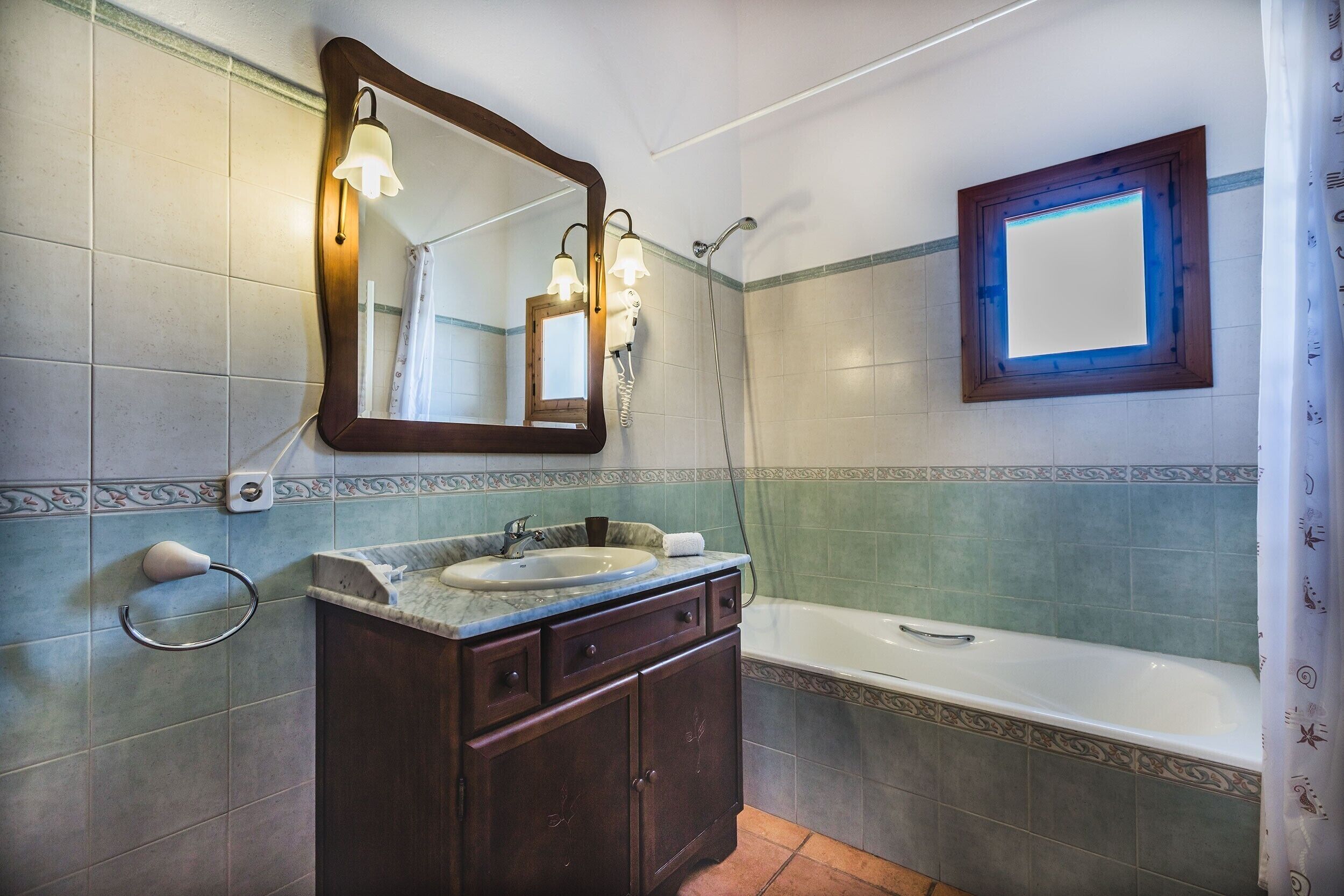 A bathroom with a sink, mirror, and shower.