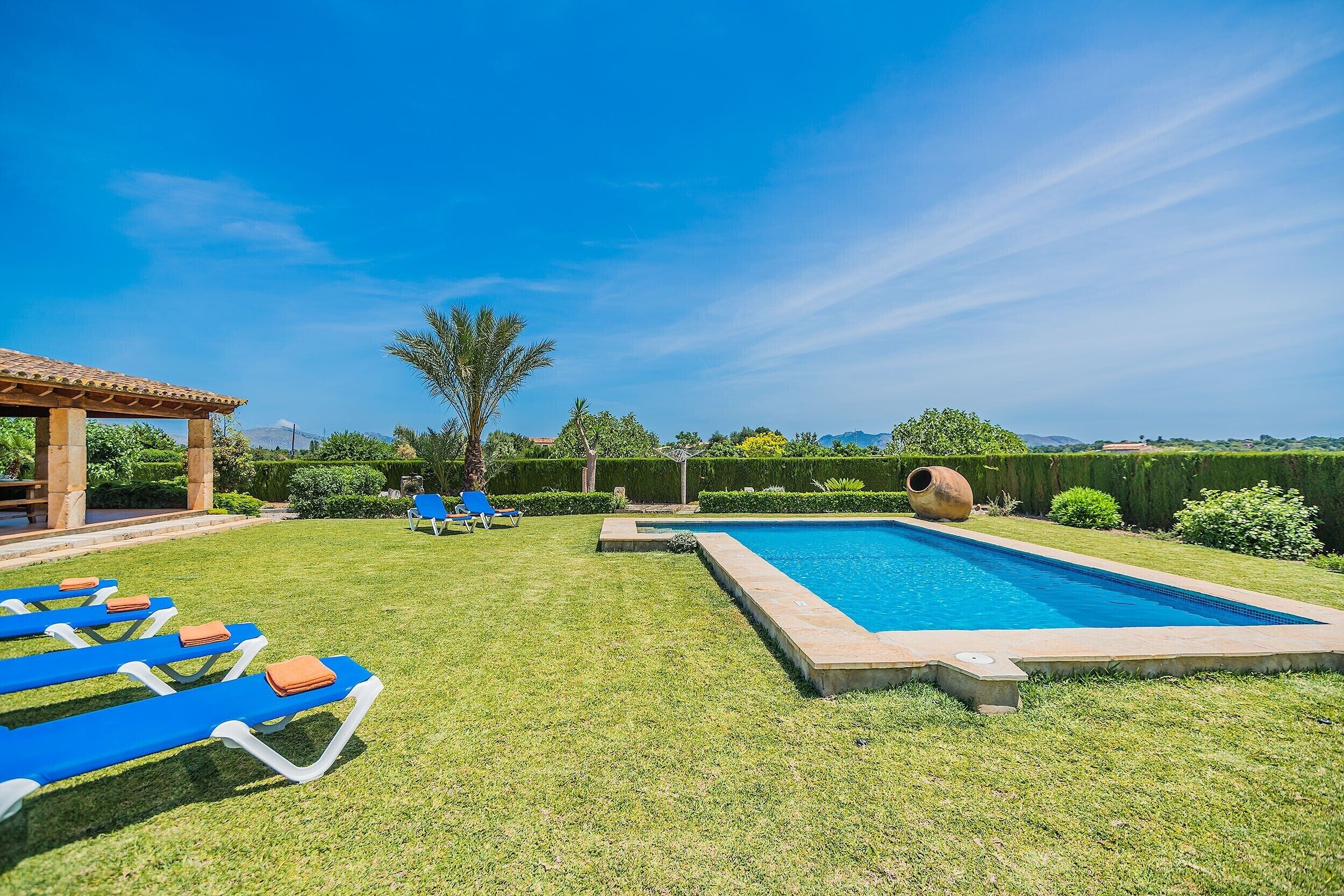 A swimming pool with lounge chairs, a pergola, and well-manicured lawn.