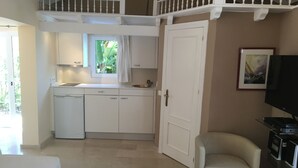 Una cocina pequeña con armarios blancos, un lavamanos y una ventana con cortinas.