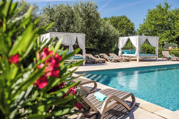 Un espace piscine avec des chaises longues et une structure en forme de tonnelle.