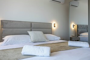 Une chambre d’hôtel comprenant un lit, deux tables de chevet, un grand miroir et un appareil de climatisation.