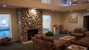 A living room with a stone fireplace, multiple sofas, and a view of a balcony.